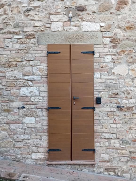 Eine Holztür an einer Steinmauer, mit einfachen Details und einem Fenster darüber.