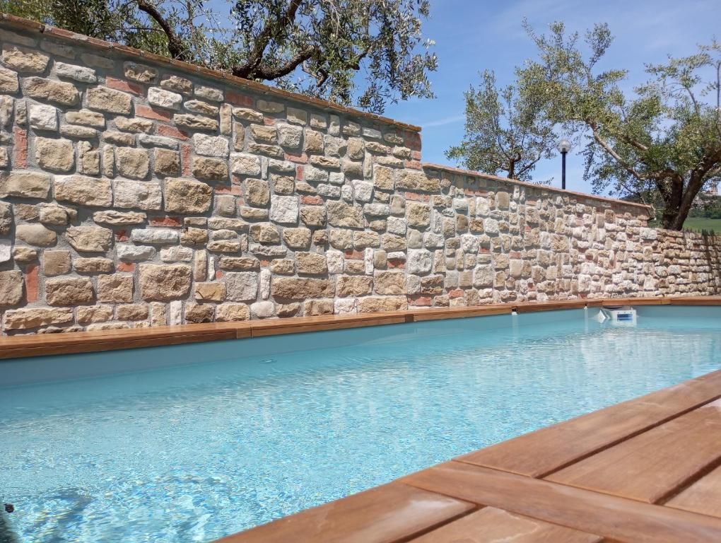 A countryside pool surrounded by a stone wall, ideal for relaxing outdoors.