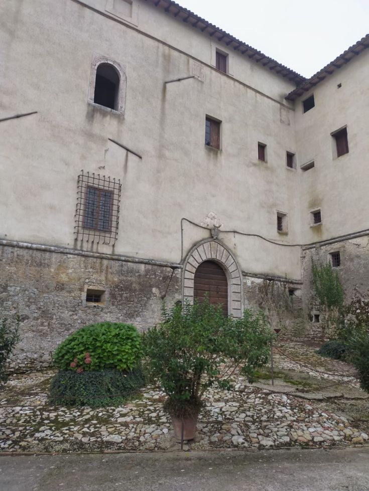 Rustic building surrounded by a garden, featuring stone paving and a serene atmosphere.