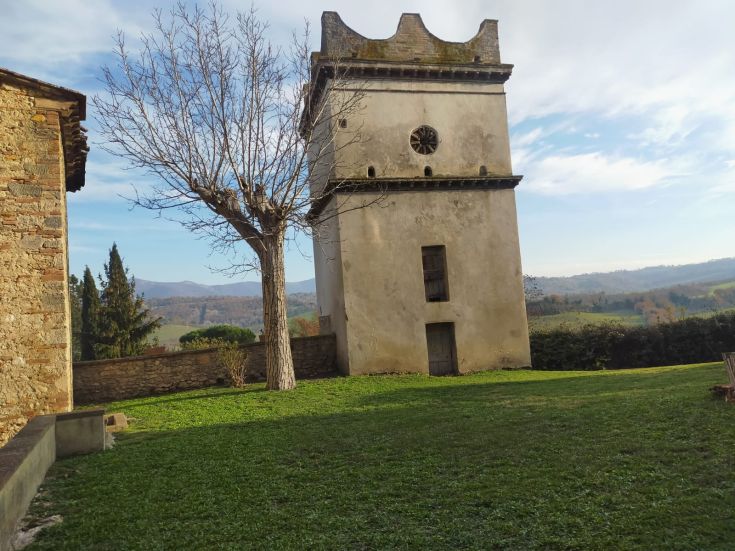 A historic tower surrounded by green grass under a clear sky. A symbol of peace and tradition in the landscape.