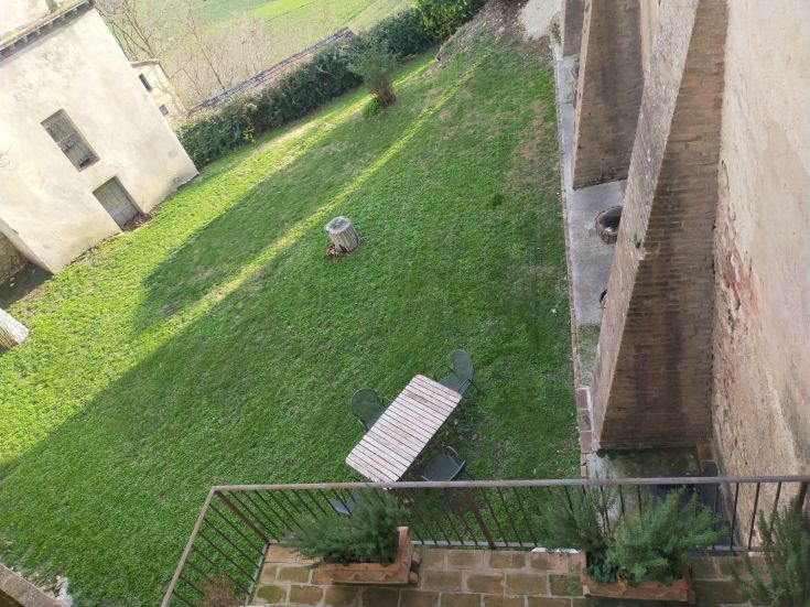 A garden equipped with a table and chairs, surrounded by nature and close to historical buildings.