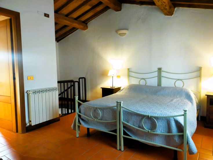 Cozy room with iron beds and wooden ceiling, featuring functional furnishings.