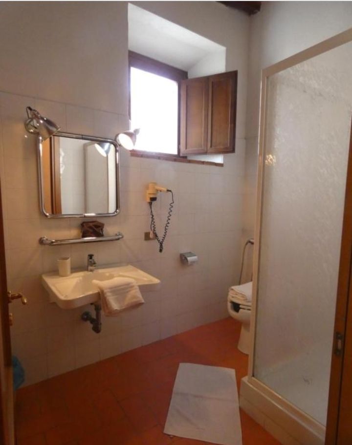 A simple bathroom featuring a shower and sink, decorated in a rustic style with natural light from the windows.