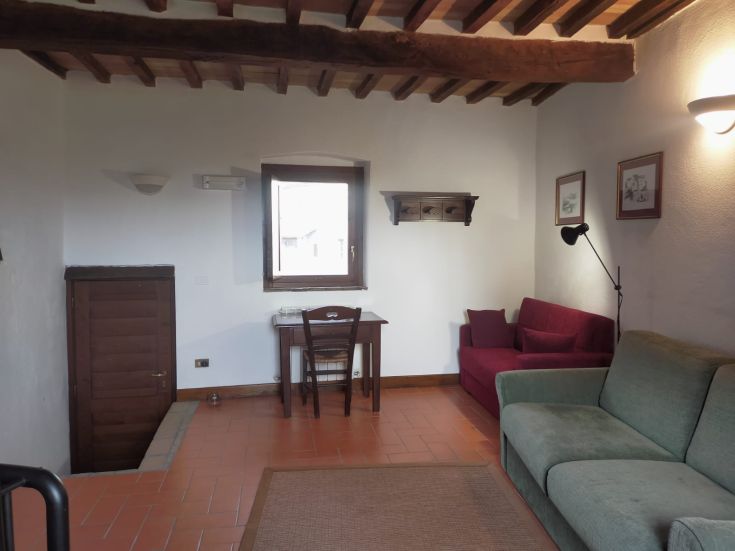 A simple living room with terracotta floors and wooden details, perfect for relaxation moments.