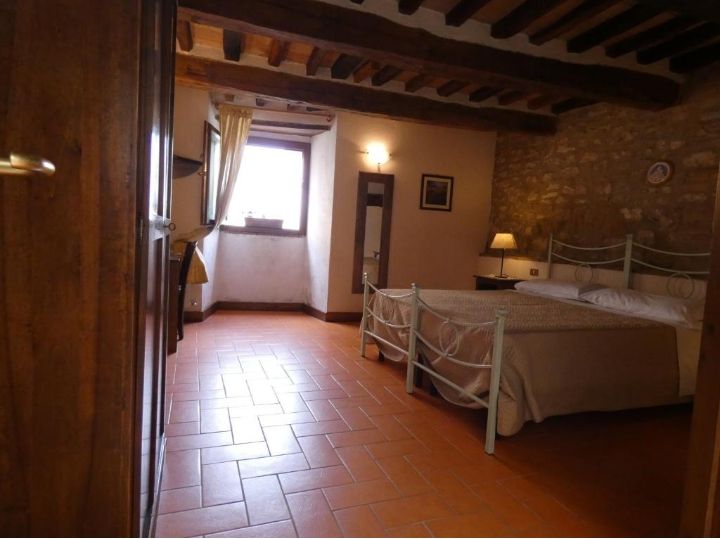 Simple room with rustic elements, featuring terracotta floor and wooden beams on the ceiling.