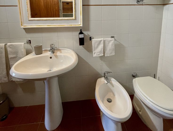 Un bagno semplice con lavabo, bidet e wc, caratterizzato da un'atmosfera ordinata e funzionale.