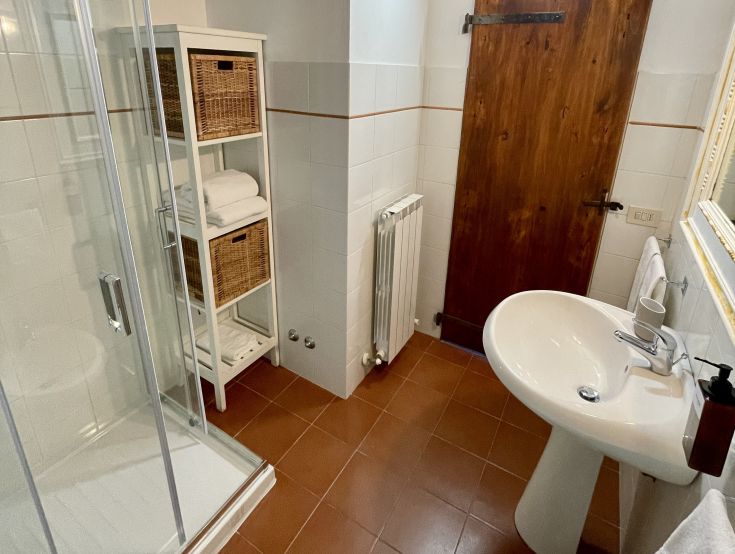 Un bagno ben arredato con una doccia spaziosa, dotato di elementi pratici per il comfort quotidiano.