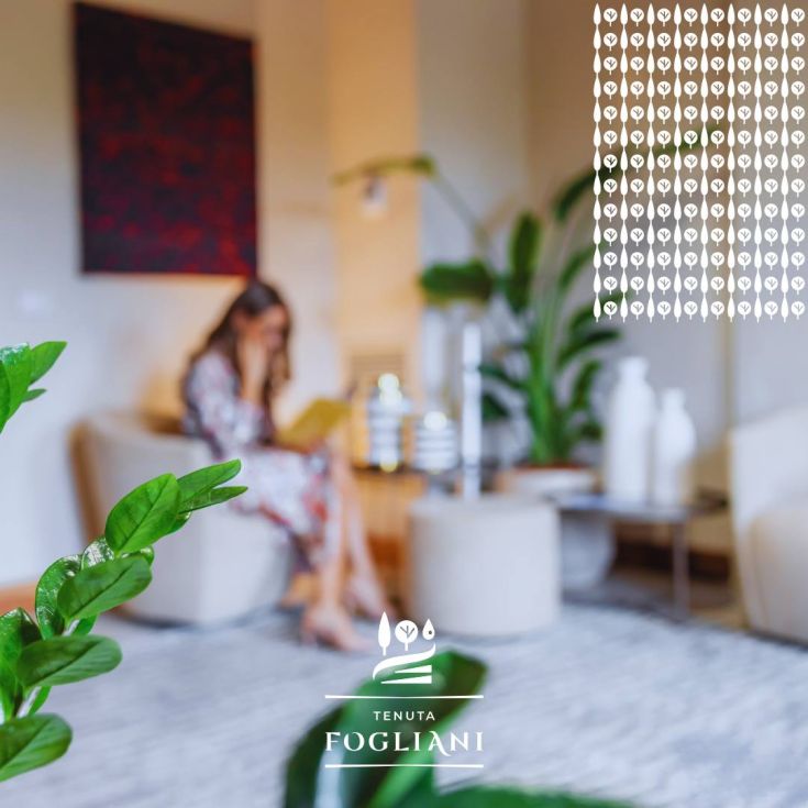Intérieur spacieux et lumineux de la Tenuta Fogliani, décoré de plantes vertes et d'une atmosphère paisible.