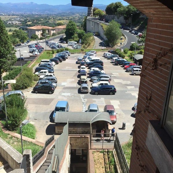 Grand parking extérieur situé dans une zone calme, surplombant une vallée verte.