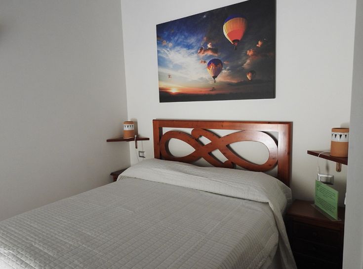 Camera semplice con letto matrimoniale e dettagli decorativi. Ideale per un soggiorno tranquillo.