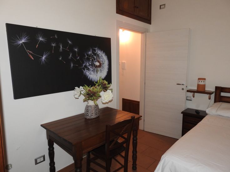 Una camera calda e confortevole, con un quadro di fiori e un tavolo in legno, ideale per momenti di relax.