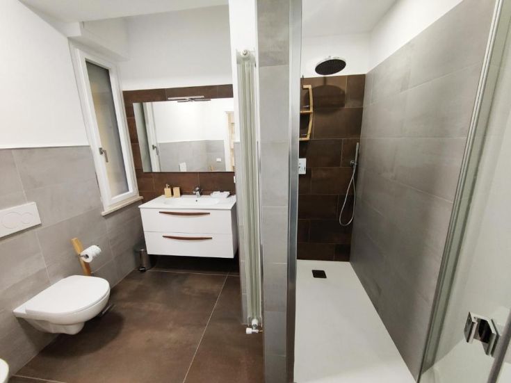 Bagno con doccia, finiture in cemento e ampio specchio.