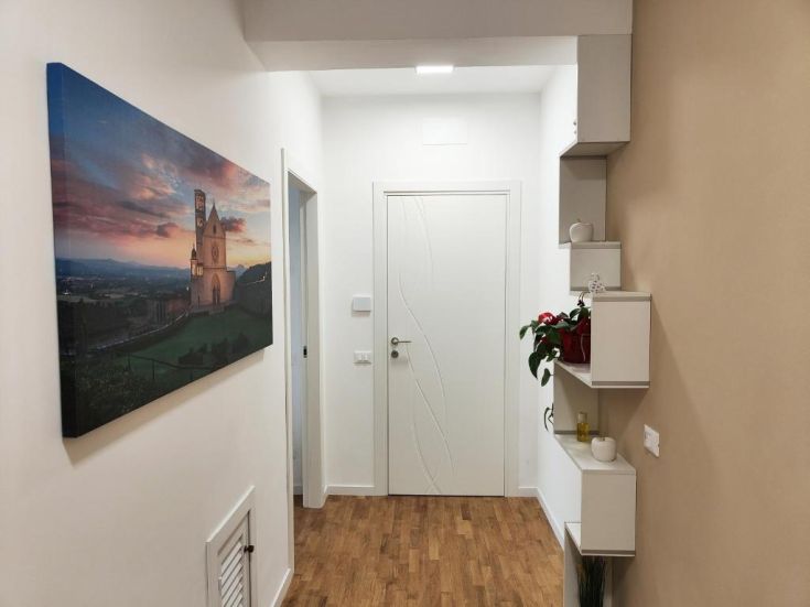 In un corridoio semplice, si nota un quadro decorativo e alcuni dettagli arredativi sobrii.