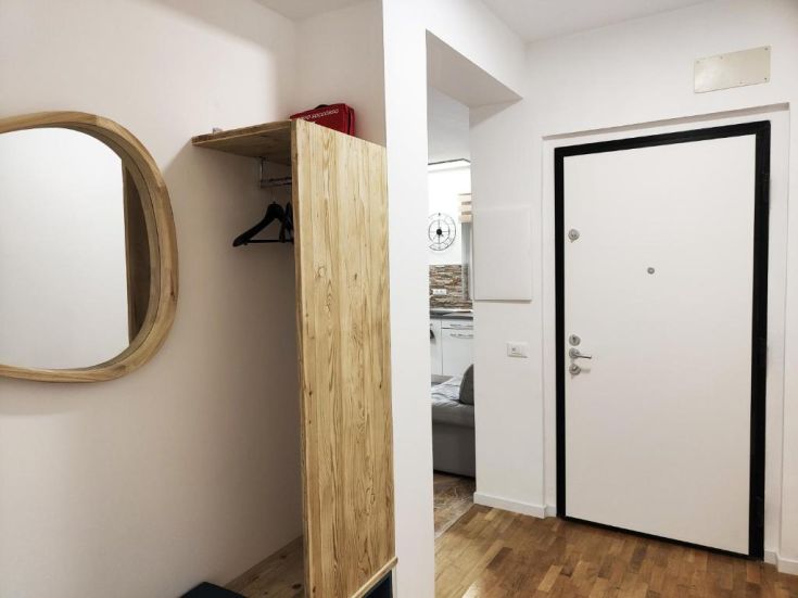 Un ingresso semplice con uno specchio e un armadio in legno chiaro.