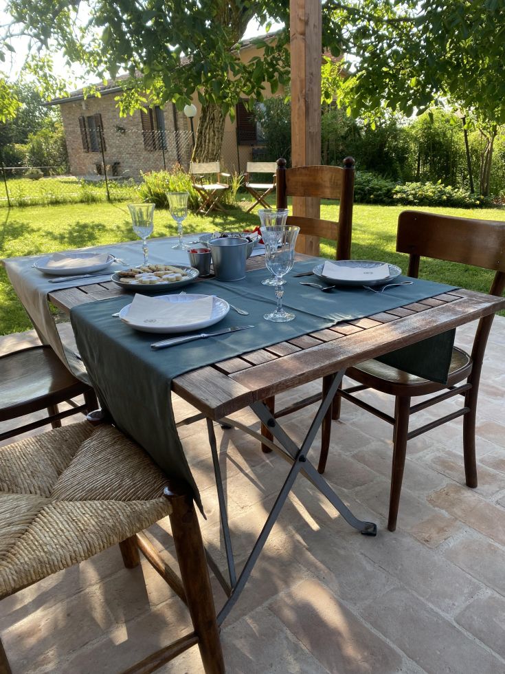 Une table en extérieur située dans un jardin verdoyant, préparée pour un repas en plein air.