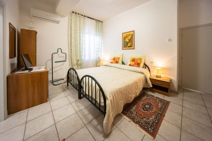 Camera tranquilla con letto matrimoniale e arredamento sobrio, adatta per un soggiorno confortevole.