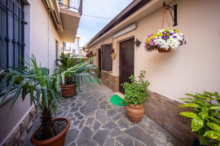 Ingresso di un'affittacamere, con piante e fiori, che conduce a stanze arredate con cura.