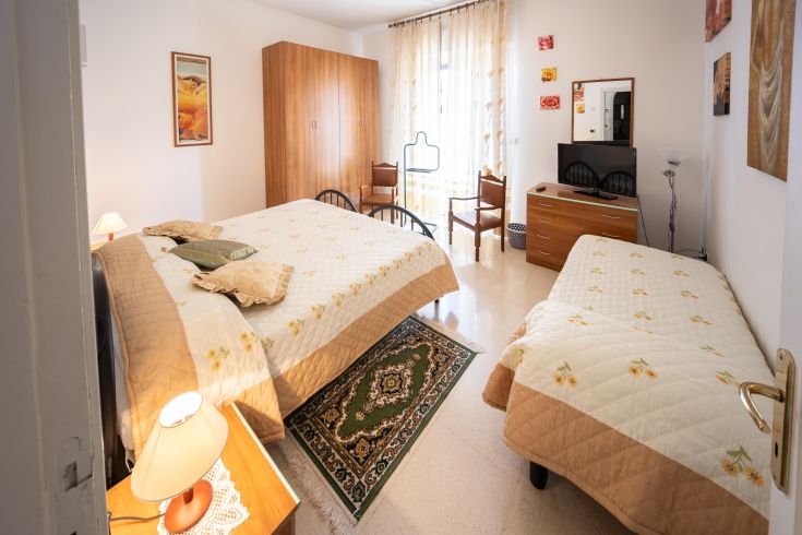 Camera semplice con due letti e tonalità calde, ideale per un soggiorno tranquillo e confortevole.