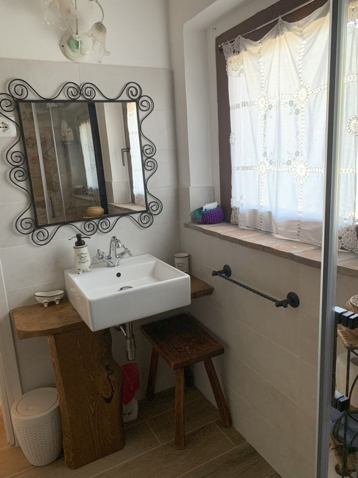 A well-lit bathroom featuring a ceramic sink and light wooden furniture.