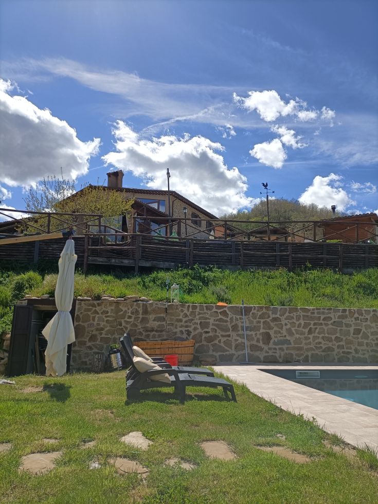 A relaxation area with pool access and a view of hills and a farmhouse.