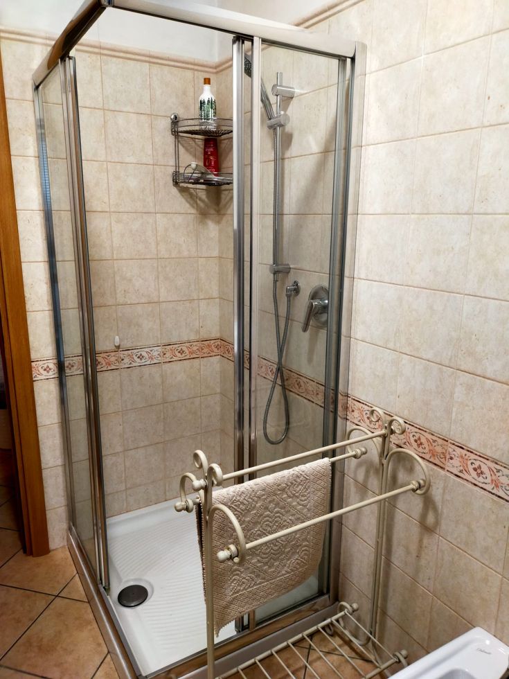 Bagno contemporaneo dotato di doccia, piastrelle chiare e accessori funzionali per un ambiente confortevole.
