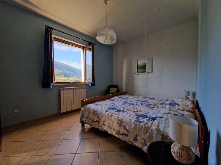Spazio interno confortevole con finestra che offre uno scorcio sul paesaggio circostante di monti e vegetazione.