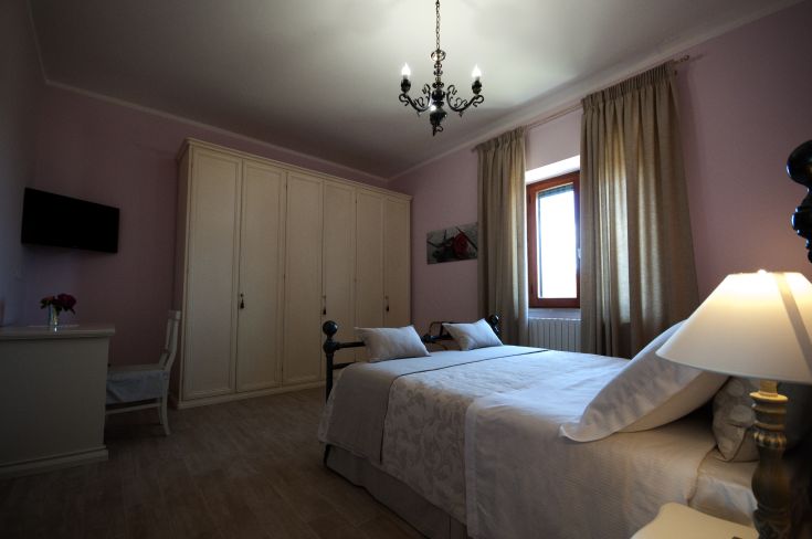 A simple and comfortable bedroom with neutral tone walls and essential furnishings.