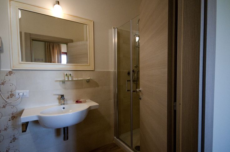 Interior of a modern bathroom featuring a shower, sink, and well-lit mirror.