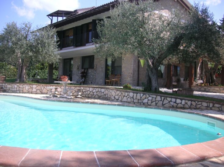Villa surrounded by trees, featuring an outdoor pool, perfect for relaxing moments outdoors.