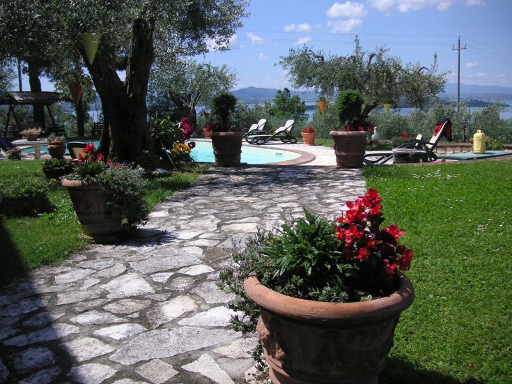 A cozy B&B surrounded by greenery, featuring a swimming pool and a view of Lake Trasimeno.