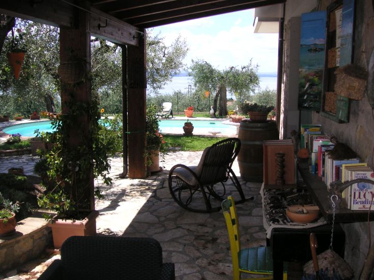 A relaxing outdoor area with a pool, surrounded by olive trees and overlooking Lake Trasimeno.