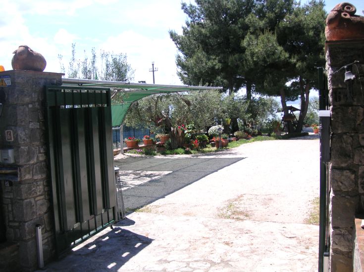 Entrance of a cozy B&B surrounded by nature, adorned with flowers, overlooking Lake Trasimeno.