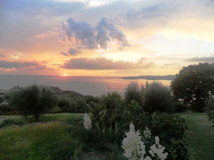 Sunset over Lake Trasimeno, with lush greenery and colors painting the sky.