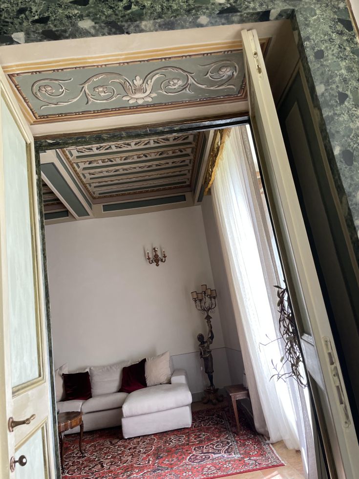 Interni del Palazzo Lauri, con soffitto decorato e arredi discreti e ben curati.