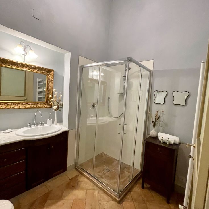 Un bagno con doccia, specchi e lavabo, arredato in modo semplice con elementi di design moderno.