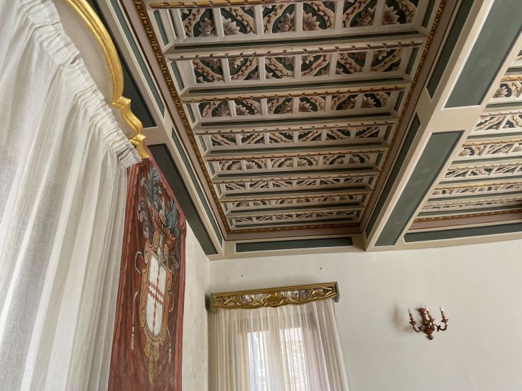 Interni del palazzo, caratterizzati da decorazioni semplici e un soffitto affrescato che ne sottolinea la storicità.
