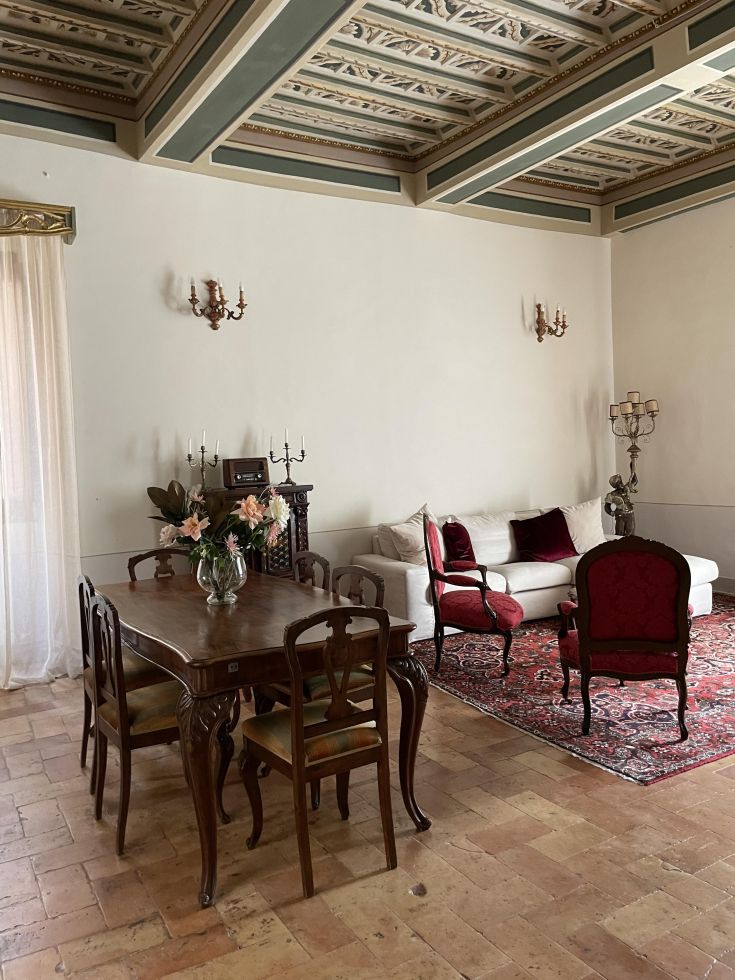 Ampio soggiorno di un appartamento situato in un palazzo storico, caratterizzato da arredi in stile classico e moderno.