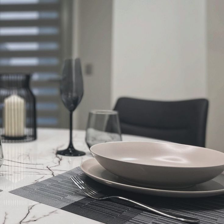 Simple plating on a contemporary table, featuring dark glasses and neutral-colored plates.