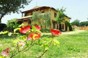 Una casa gialla rilassante con un giardino curato, caratterizzato da fiori colorati e aree verdi ben curate.