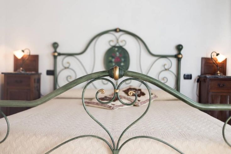 Una camera da letto semplice con letto in ferro battuto e comodini decorativi.
