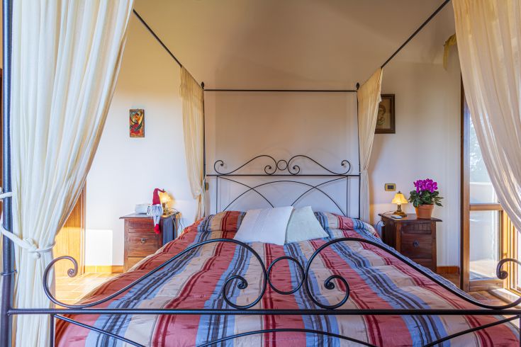 Stanza da letto semplice con letto a baldacchino e tonalità calde.