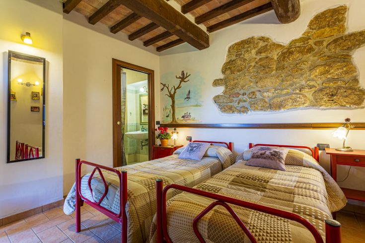 Camera tranquilla con letti singoli, semplice arredamento e luminosità naturale.