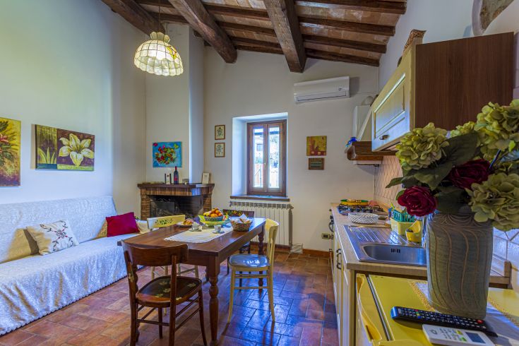 Una cucina-soggiorno semplice e accogliente, arredata con mobili in legno e decorazioni floreali.