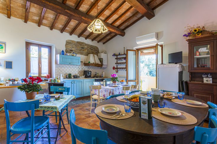 Cucina in stile rustico, caratterizzata da tavoli in legno e dettagli vivaci, ideale per accogliere pasti in compagnia.