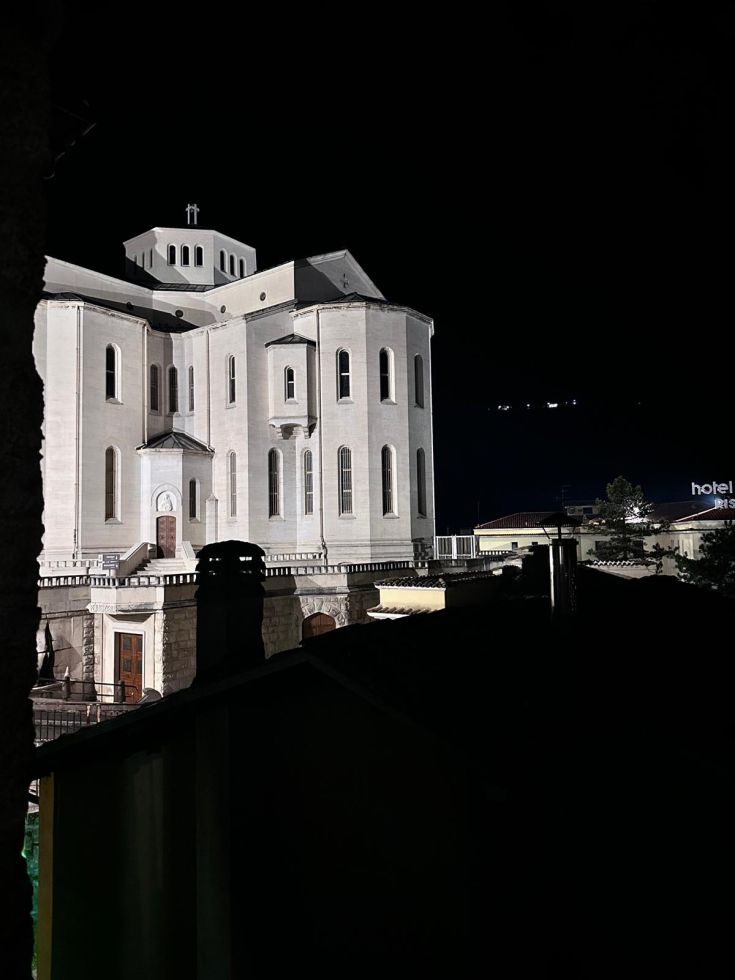 Un edificio storico ben illuminato di sera, situato nei pressi della Basilica di Santa Rita a Cascia.