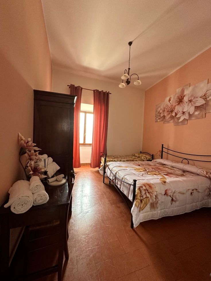 Camera confortevole con decorazioni floreali e una finestra che lascia entrare luce naturale, perfetta per un soggiorno tranquillo.