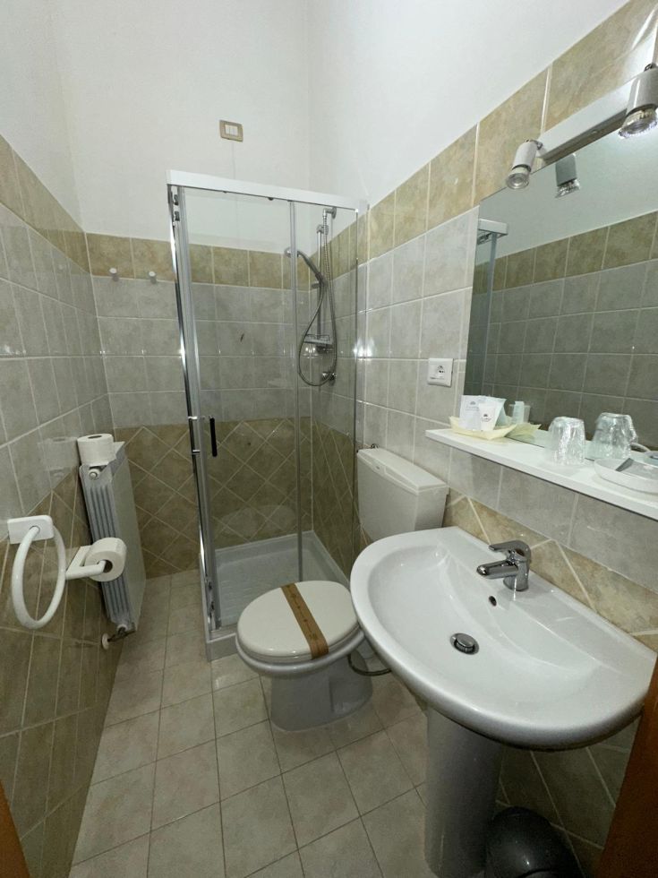 Bagno semplice con arredi moderni, dotato di doccia e sanitari funzionali.