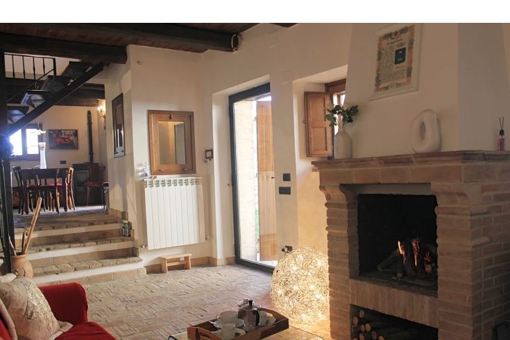 Simple living room with a fireplace, furnished with practical elements, located in a typical Umbrian cottage.