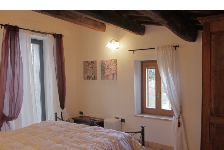 A simple room with light walls and windows overlooking a well-kept garden.