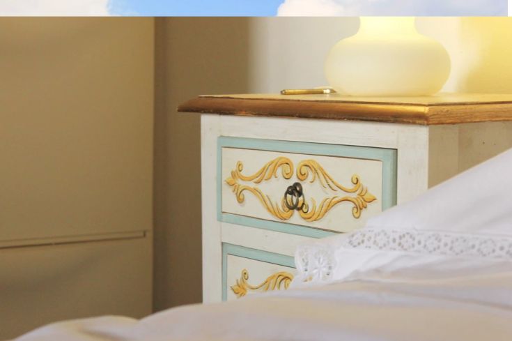 A wooden furniture occupies the room, illuminated by warm light, with a bed prepared for the evening.